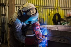 man welding a large metal barrel