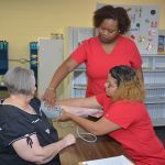 Instructor Erica Fleming helping a pharmacy student take a woman's blood pressure