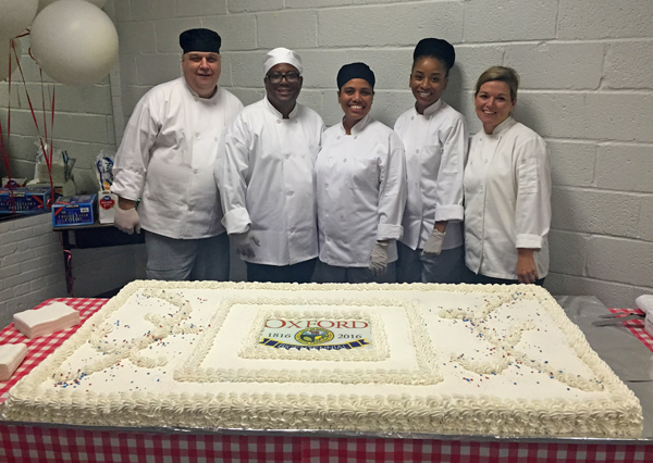 Culinary Arts students and instructor pose with a huge cake for Oxford's bicentennial.