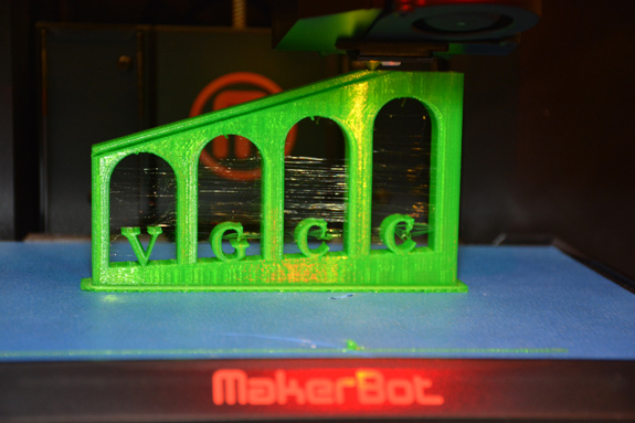 A 3-D printer builds a green model of the VGCC arches logo during the Business Technologies Fair. The model was programmed by Brandon Carver of Durham, a student in the college’s Simulation & Game Development program. (VGCC photo)