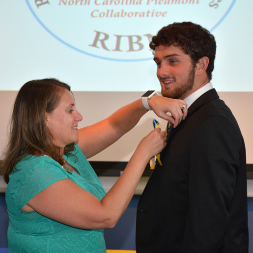 Erica Jastrow pins Jonathan Carlock with a ribbon indicating his induction.