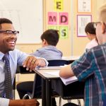 Teacher smiling at student sitting a desk